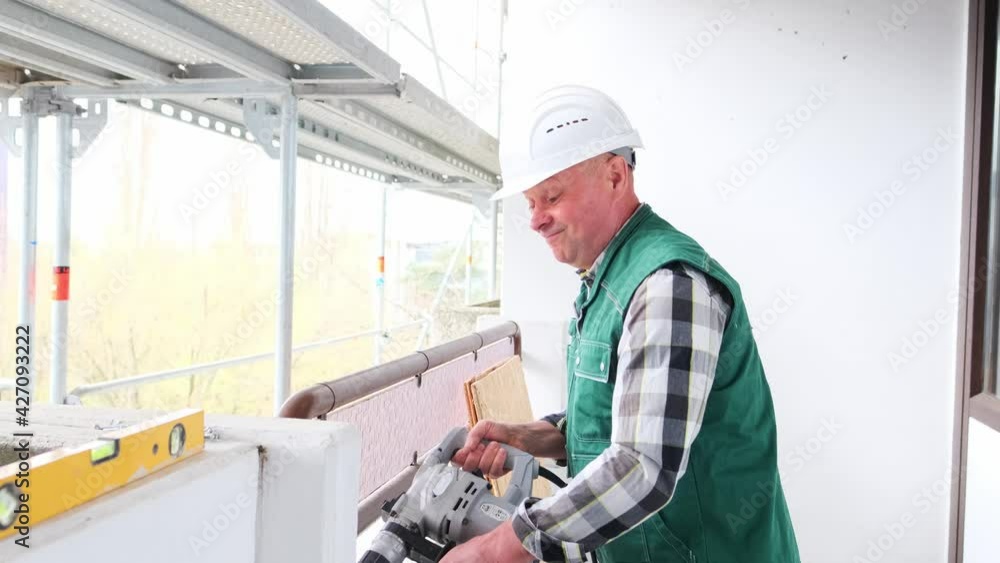 elderly construction worker with hand tool in white helmet protection and working uniform works at construction site for construction and repair of buildings, civil engineering concept elderly construction worker with hand tool in white helmet protection and working uniform works at construction site for construction and repair of buildings, civil engineering concept