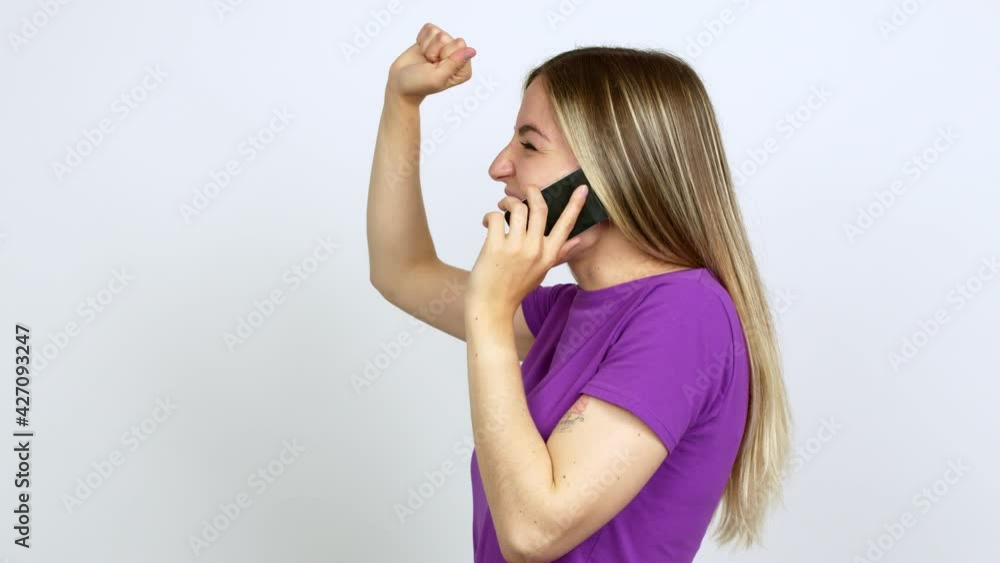 Young woman talking on mobile phone celebrating a victory over isolated background Young woman talking on mobile phone celebrating a victory over isolated background