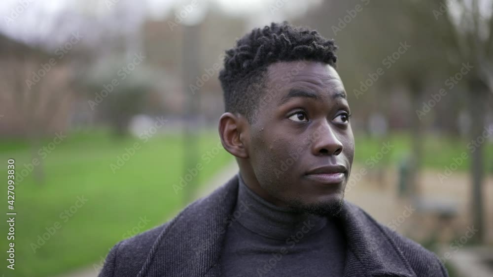 Young black man walking outside at park nature wearing coat during winter season Young black man walking outside at park nature wearing coat during winter season