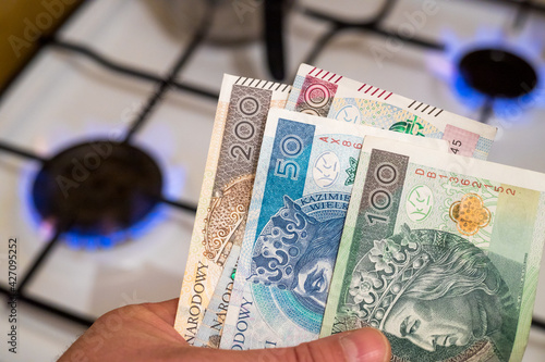 Polish money held against the background of a gas stove. The concept of rising gas prices