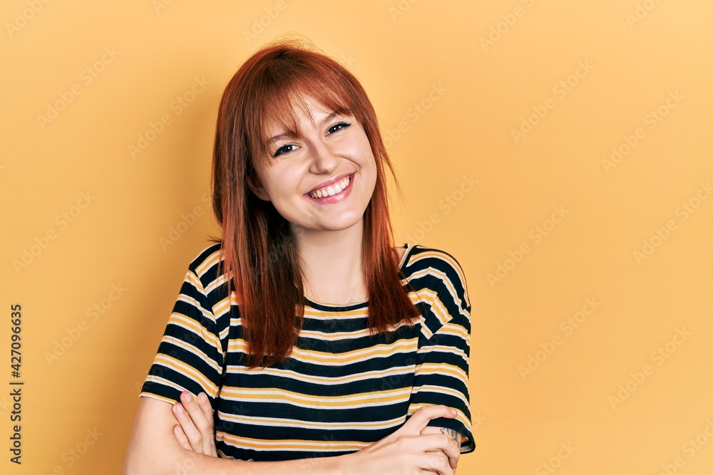 Redhead young woman wearing casual striped t shirt happy face smiling with crossed arms looking at the camera. positive person. Redhead young woman wearing casual striped t shirt happy face smiling with crossed arms looking at the camera. positive person.