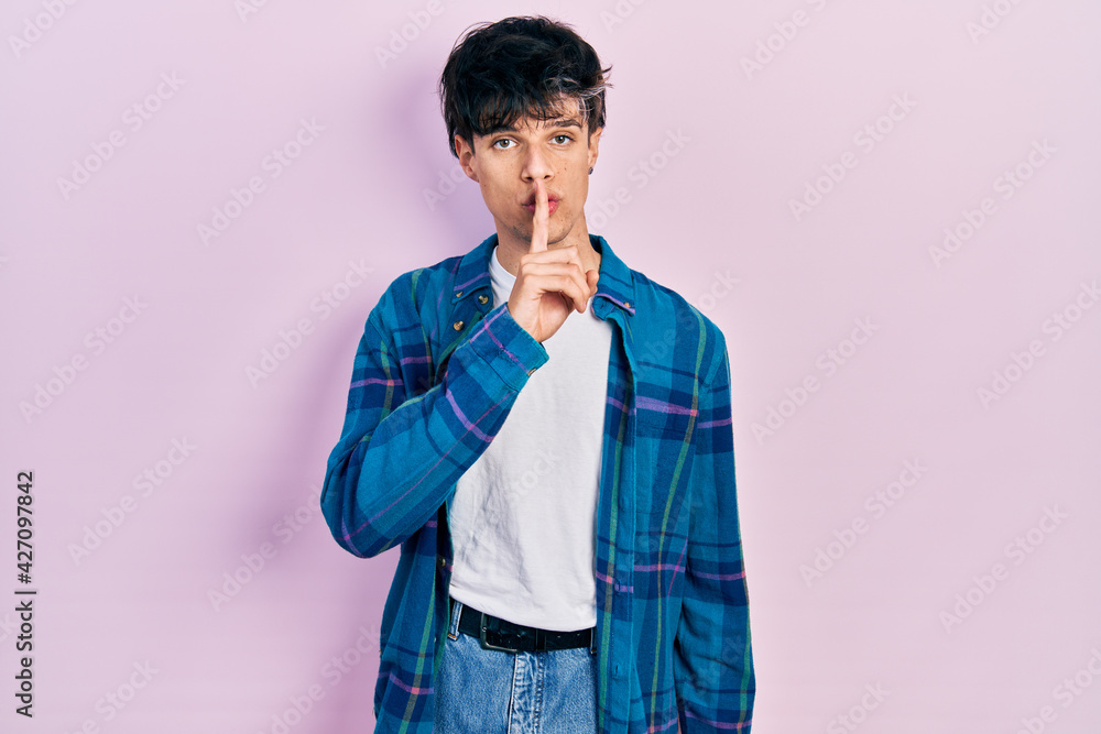 Handsome hipster young man wearing casual white t shirt and vintage shirt asking to be quiet with finger on lips. silence and secret concept. Handsome hipster young man wearing casual white t shirt and vintage shirt asking to be quiet with finger on lips. silence and secret concept.