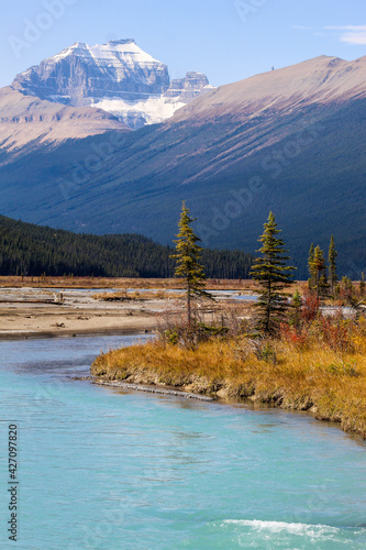 Turquoise blue glacial river with beautiful Canadian Rockies / Rocky Mountains showing snow capped mountains © Muskoka