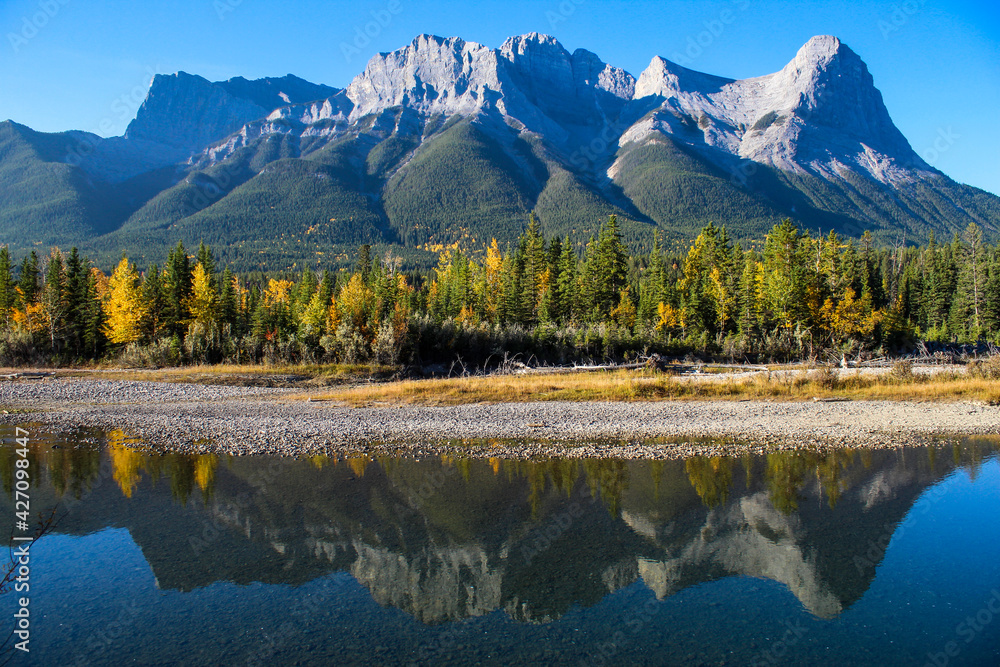 Fototapeta premium River reflection with mountains and colourful autumn trees on sunny blue sky day 