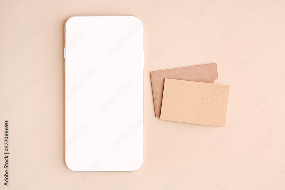 Mobile phone mockup with blank screen and business cards isolated on beige paper. Business card made of craft paper and smart phone. High quality photo Mobile phone mockup with blank screen and business cards isolated on beige paper. Business card made of craft paper and smart phone. High quality photo