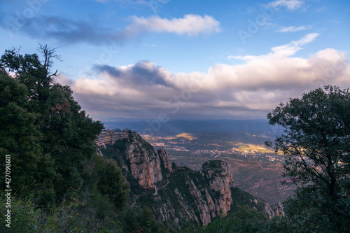 Aerial view of the Montserrat mountains on a beautiful spring day  Catalonia  Spain. Dramatic sky over the mountains. Sunlight falls through the clouds on the ground and mountains.