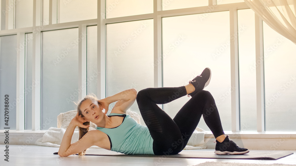 Obraz premium A Girl in a Sports Uniform Does Exercises for the Abdominal Press at Home, Does Exercises, Leads a Healthy Lifestyle. Athletic Woman Performing Gymnastic Exercises Indoors