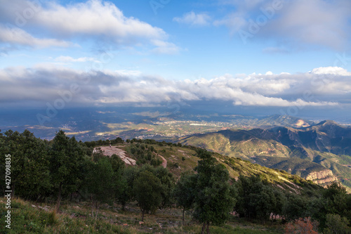 Aerial view of the Montserrat mountains on a beautiful spring day, Catalonia, Spain. Dramatic sky over the mountains. Sunlight falls through the clouds on the ground and mountains.