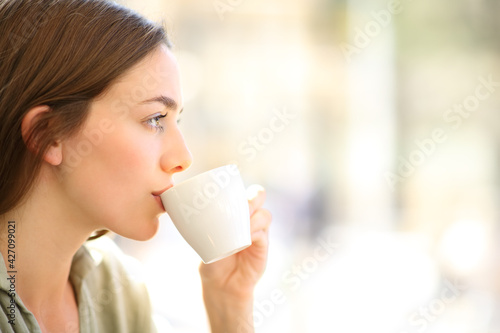 Woman drinking coffee sipping from cup in a bar