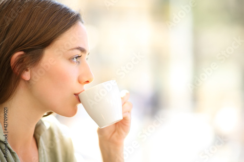 Foto Woman drinking coffee sipping from cup in a bar