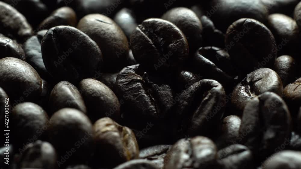 Coffee beans in rotation. Mixed Robusta and Arabica roasted Coffee beans. Coffee background. Coffee backdrop. Close up.