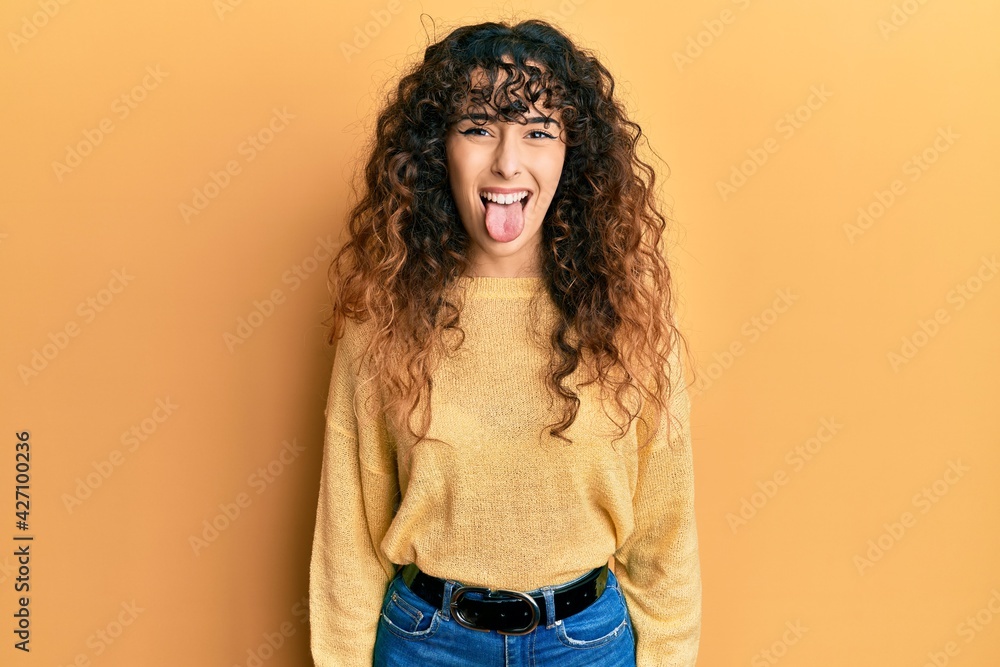 Young hispanic girl wearing casual clothes sticking tongue out happy with funny expression. emotion concept.