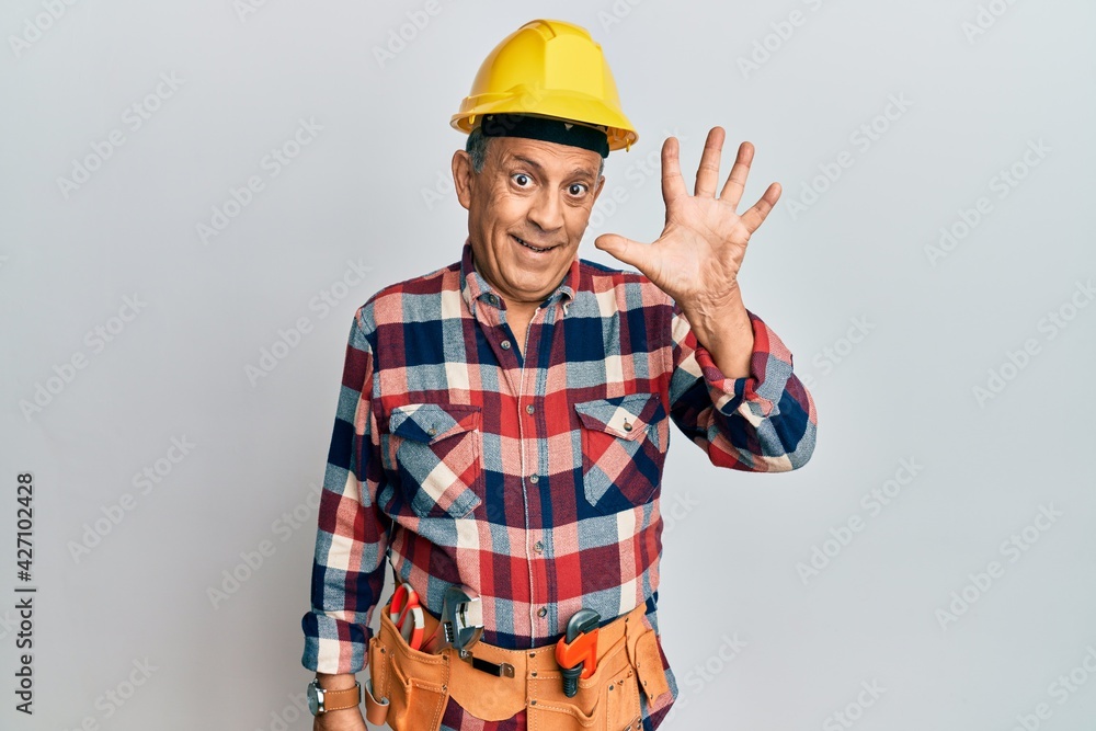 Senior hispanic man wearing handyman uniform showing and pointing up with fingers number five while smiling confident and happy. Senior hispanic man wearing handyman uniform showing and pointing up with fingers number five while smiling confident and happy.