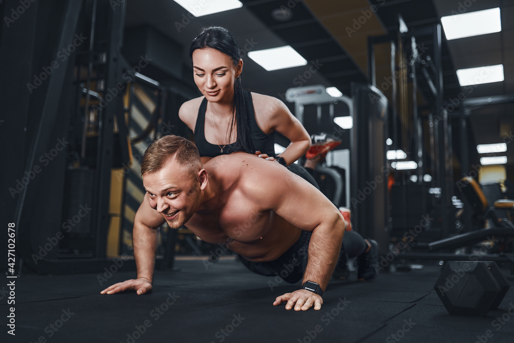 Young muscular man doing push-up exercise and holding girl. joint training. Group lessons. Teambuilding. romance. Young muscular man doing push-up exercise and holding girl. joint training. Group lessons. Teambuilding. romance.