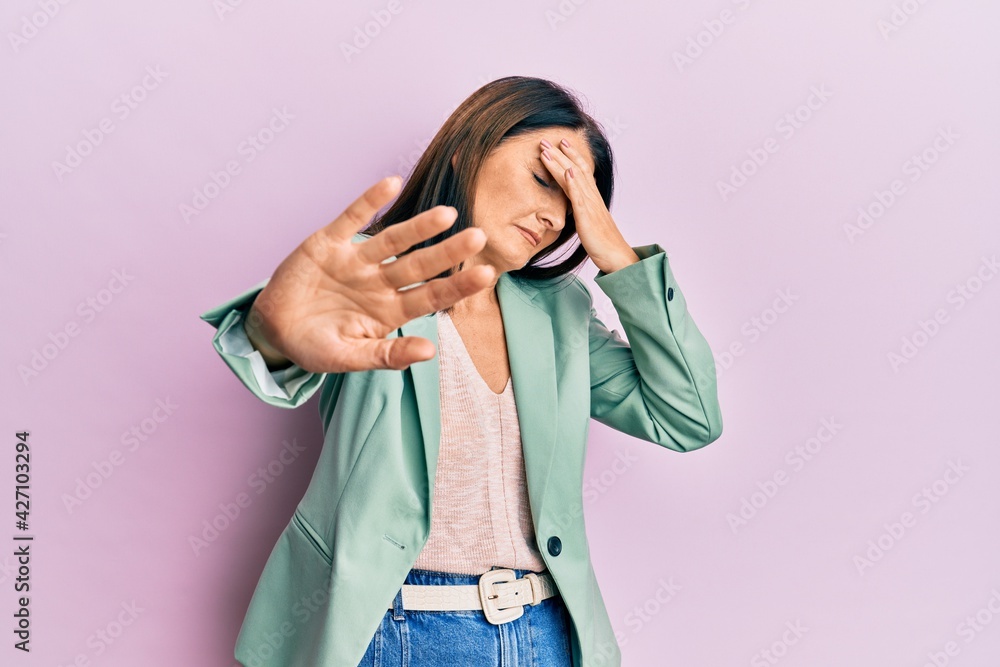 Middle age brunette woman wearing casual clothes covering eyes with hands and doing stop gesture with sad and fear expression. embarrassed and negative concept. Middle age brunette woman wearing casual clothes covering eyes with hands and doing stop gesture with sad and fear expression. embarrassed and negative concept.