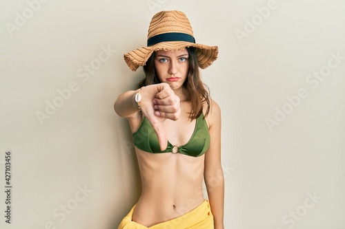 Young brunette woman wearing bikini looking unhappy and angry showing rejection and negative with thumbs down gesture. bad expression.