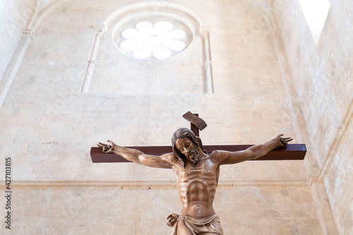 Suggestivo crocifisso di legno in basso con in alto un rosonesplendente di luce di una abbazia medievale