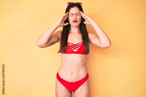Young beautiful caucasian woman wearing bikini suffering from headache desperate and stressed because pain and migraine. hands on head.