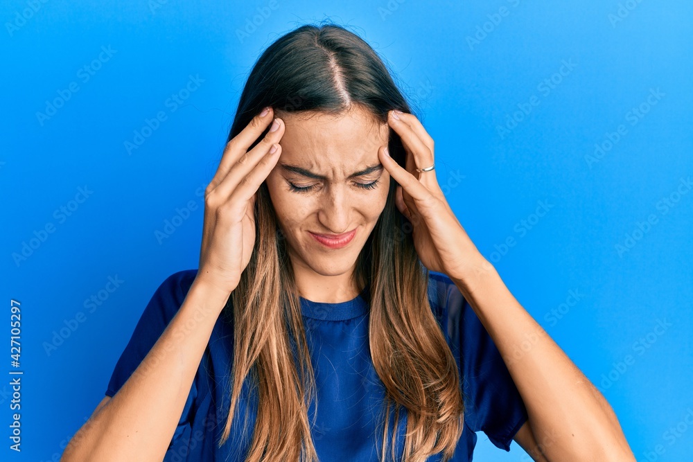 Young beautiful woman wearing casual clothes suffering from headache desperate and stressed because pain and migraine. hands on head. Young beautiful woman wearing casual clothes suffering from headache desperate and stressed because pain and migraine. hands on head.