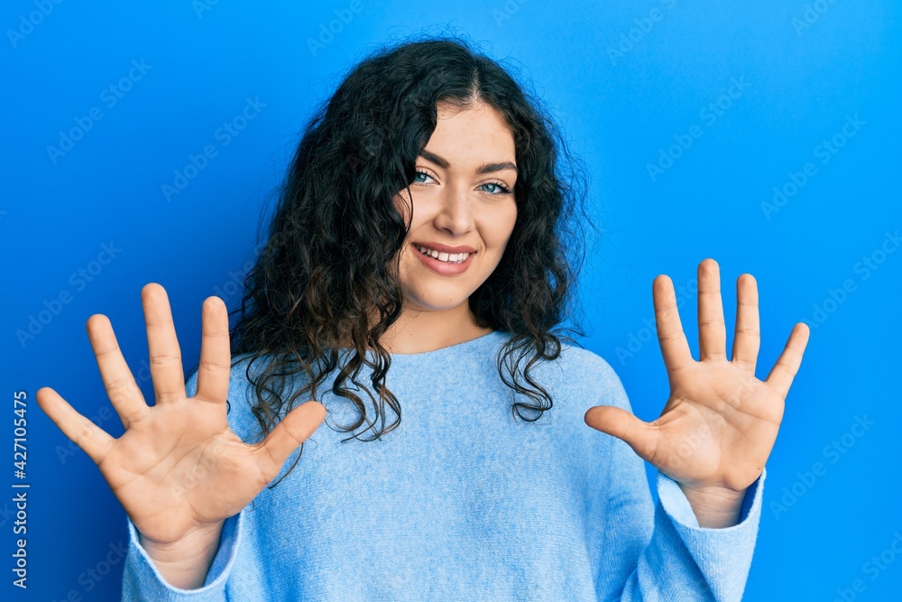 Young brunette woman with curly hair wearing casual clothes showing and pointing up with fingers number ten while smiling confident and happy. Young brunette woman with curly hair wearing casual clothes showing and pointing up with fingers number ten while smiling confident and happy.