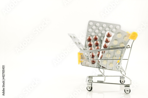 capsules,pills,medicines in blisters on white background in shopping cart. Pharmacy,people and health concept.Online ordering of medicines,online shopping.Vitamins and dietary supplements.Copy space.