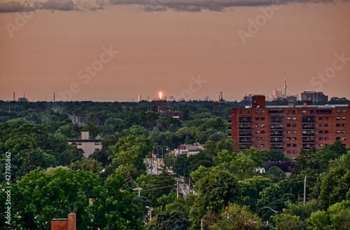 The Toronto skyline with the CN tower seen in the distance from the west as the sun sets on a sping day over a lush urban forest © Stephen Jackson