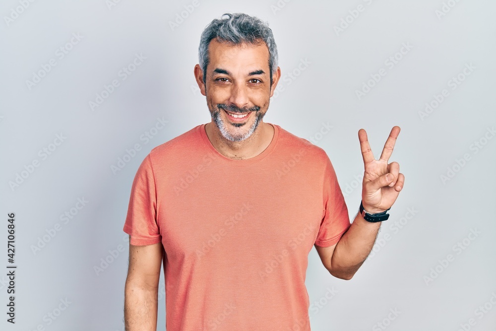 Handsome middle age man with grey hair wearing casual t shirt showing and pointing up with fingers number two while smiling confident and happy. Handsome middle age man with grey hair wearing casual t shirt showing and pointing up with fingers number two while smiling confident and happy.