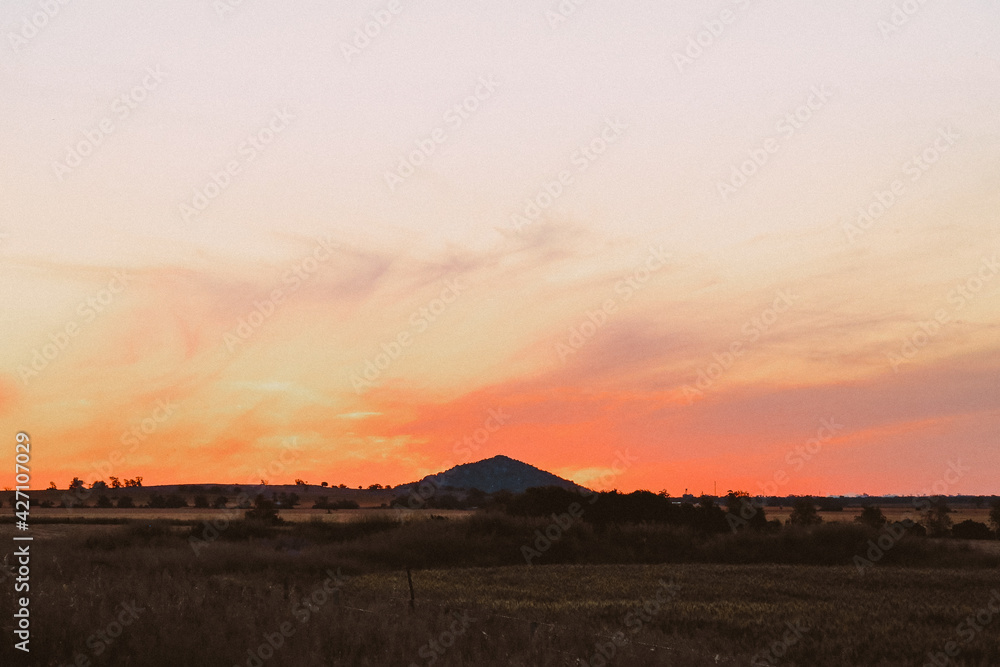 Silhouette of Pyramid Hill rock formation with vibrant red sunset