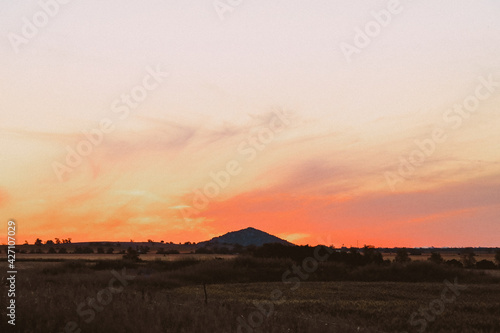 Silhouette of Pyramid Hill rock formation with vibrant red sunset