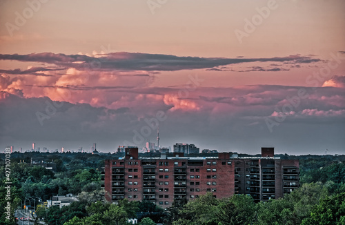 Storm clouds form over the Toronto skyline in the far distance on a moody summer evening before a thunderstorm