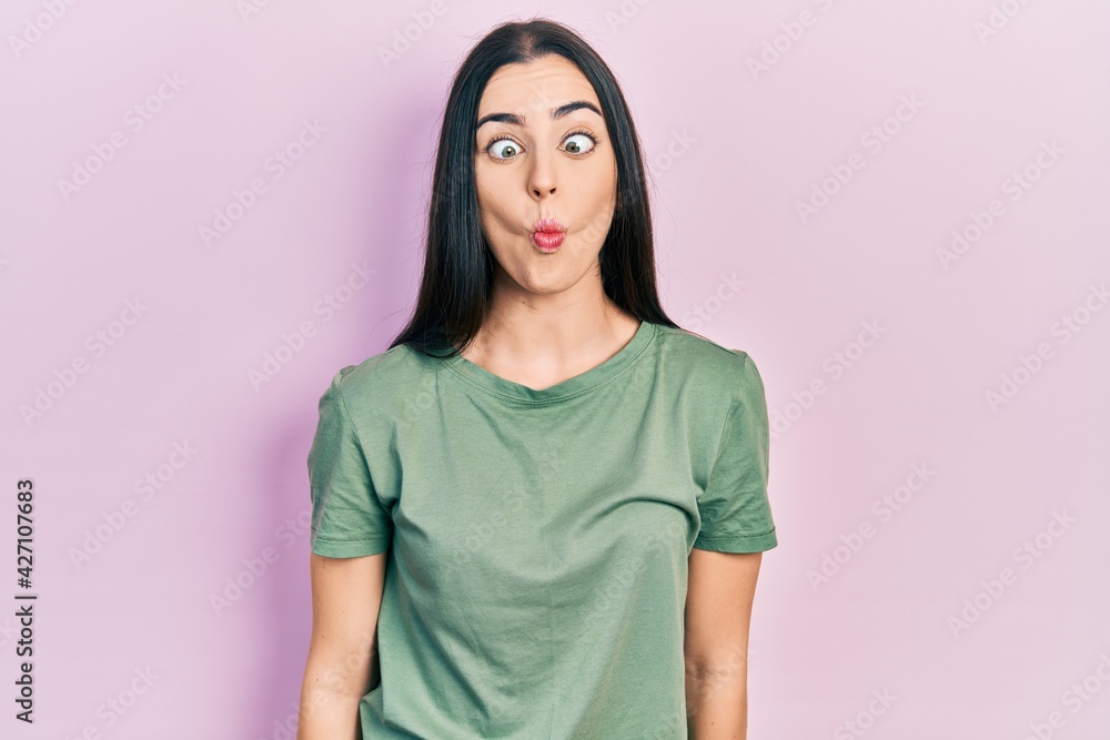 Beautiful woman with blue eyes wearing casual t shirt making fish face with lips, crazy and comical gesture. funny expression. Beautiful woman with blue eyes wearing casual t shirt making fish face with lips, crazy and comical gesture. funny expression.