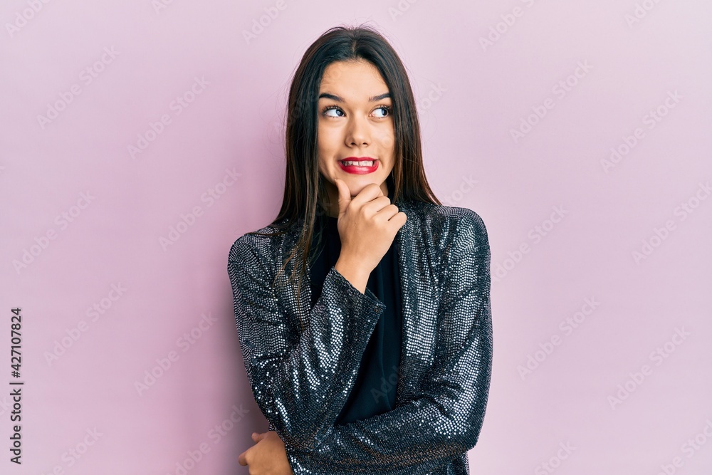 Young hispanic girl wearing party jacket with hand on chin thinking about question, pensive expression. smiling with thoughtful face. doubt concept. Young hispanic girl wearing party jacket with hand on chin thinking about question, pensive expression. smiling with thoughtful face. doubt concept.