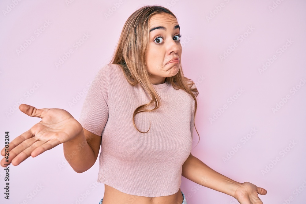 Young beautiful blonde woman wearing casual clothes clueless and confused expression with arms and hands raised. doubt concept. Young beautiful blonde woman wearing casual clothes clueless and confused expression with arms and hands raised. doubt concept.