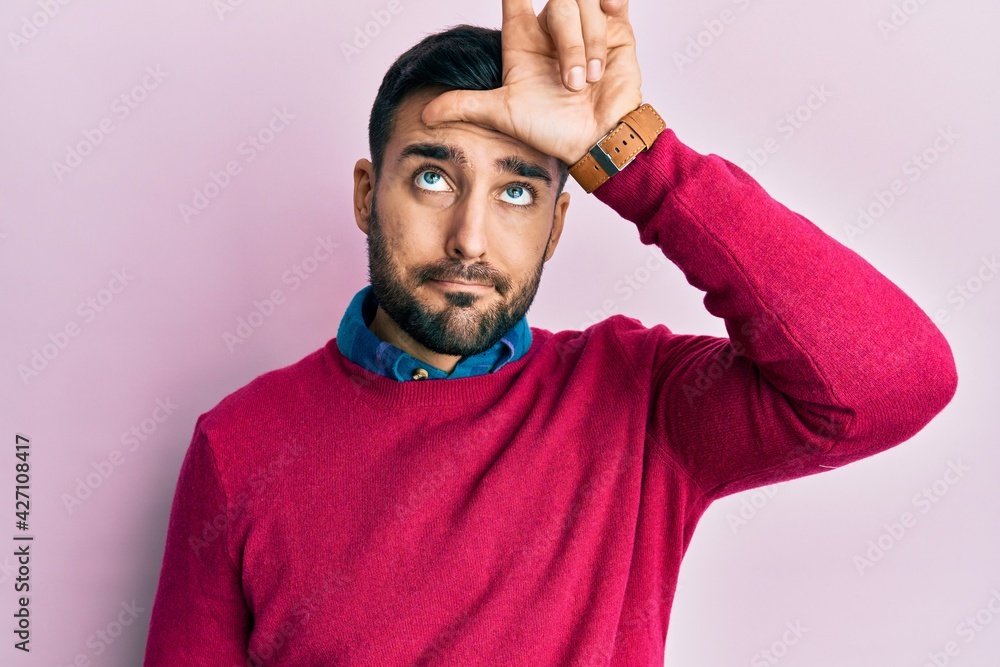 Young hispanic man wearing casual clothes making fun of people with fingers on forehead doing loser gesture mocking and insulting. Young hispanic man wearing casual clothes making fun of people with fingers on forehead doing loser gesture mocking and insulting.