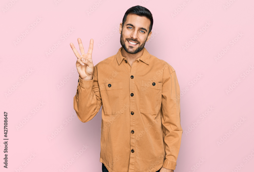 Young hispanic man wearing casual clothes showing and pointing up with fingers number three while smiling confident and happy. Young hispanic man wearing casual clothes showing and pointing up with fingers number three while smiling confident and happy.