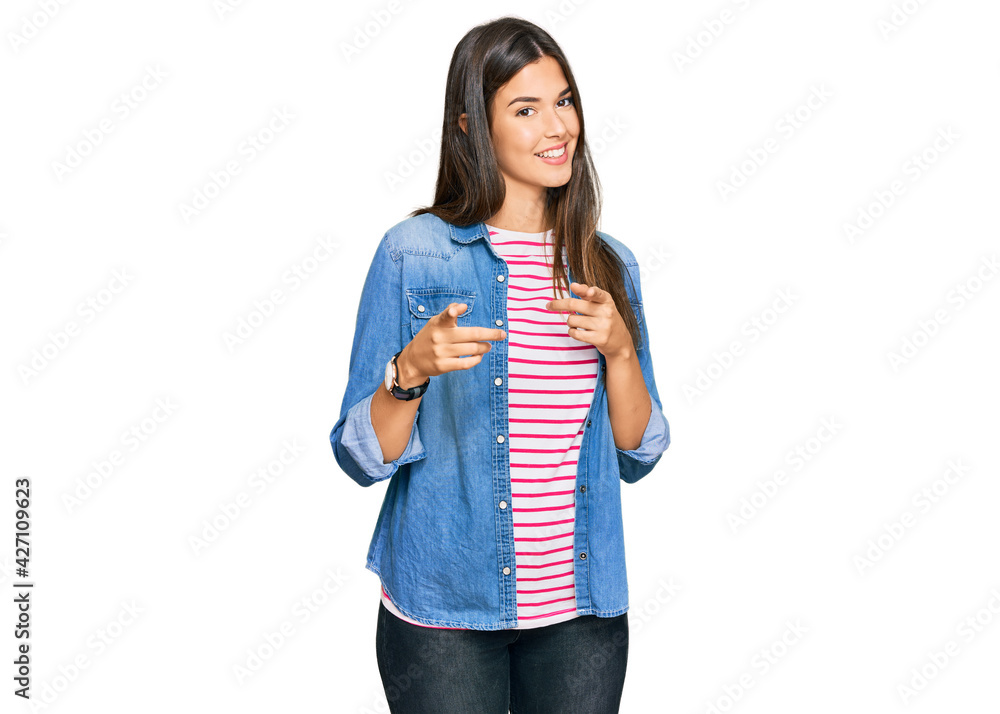 Young brunette woman wearing casual clothes pointing fingers to camera with happy and funny face. good energy and vibes. Young brunette woman wearing casual clothes pointing fingers to camera with happy and funny face. good energy and vibes.
