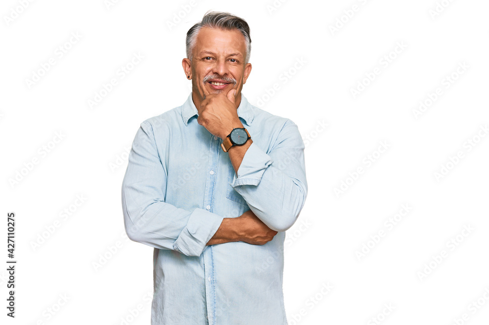Middle age grey-haired man wearing casual clothes looking confident at the camera smiling with crossed arms and hand raised on chin. thinking positive. Middle age grey-haired man wearing casual clothes looking confident at the camera smiling with crossed arms and hand raised on chin. thinking positive.