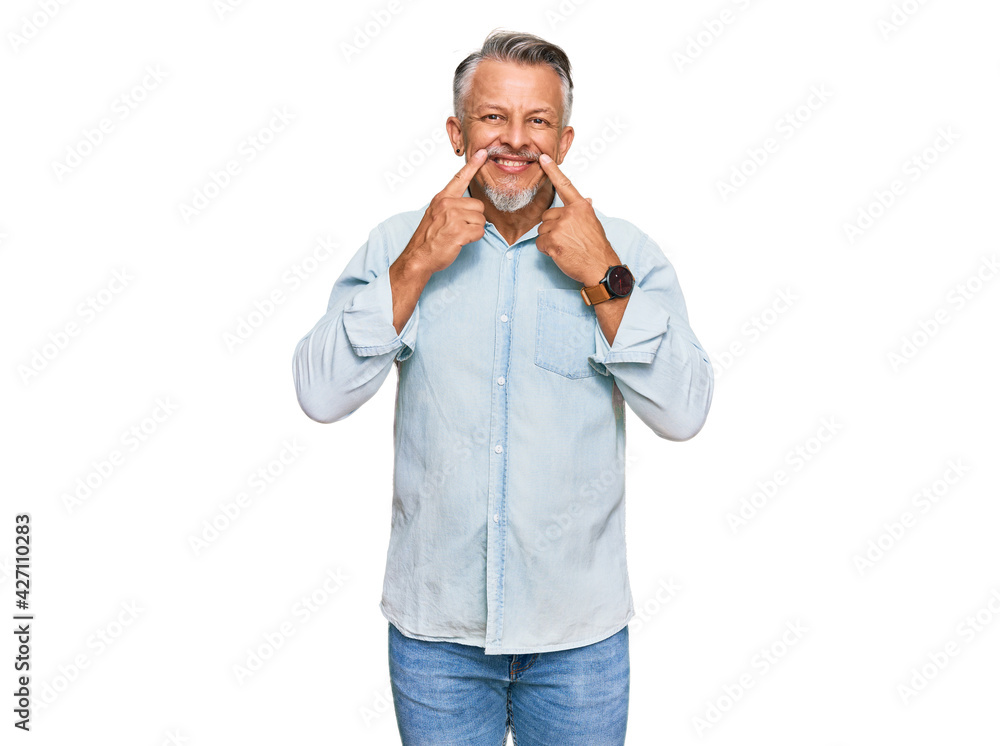Middle age grey-haired man wearing casual clothes smiling with open mouth, fingers pointing and forcing cheerful smile Middle age grey-haired man wearing casual clothes smiling with open mouth, fingers pointing and forcing cheerful smile