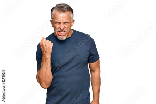 Middle age grey-haired man wearing casual clothes angry and mad raising fist frustrated and furious while shouting with anger. rage and aggressive concept.