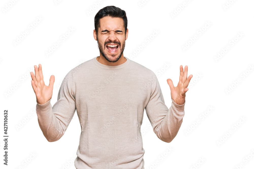 Young hispanic man wearing casual clothes celebrating mad and crazy for success with arms raised and closed eyes screaming excited. winner concept Young hispanic man wearing casual clothes celebrating mad and crazy for success with arms raised and closed eyes screaming excited. winner concept