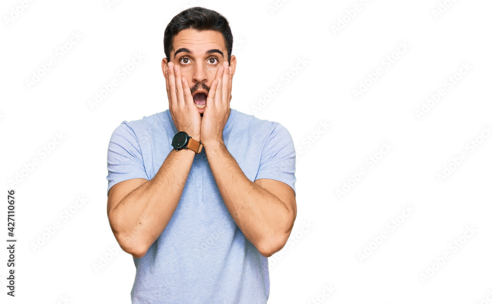 Young hispanic man wearing casual clothes afraid and shocked, surprise and amazed expression with hands on face Young hispanic man wearing casual clothes afraid and shocked, surprise and amazed expression with hands on face
