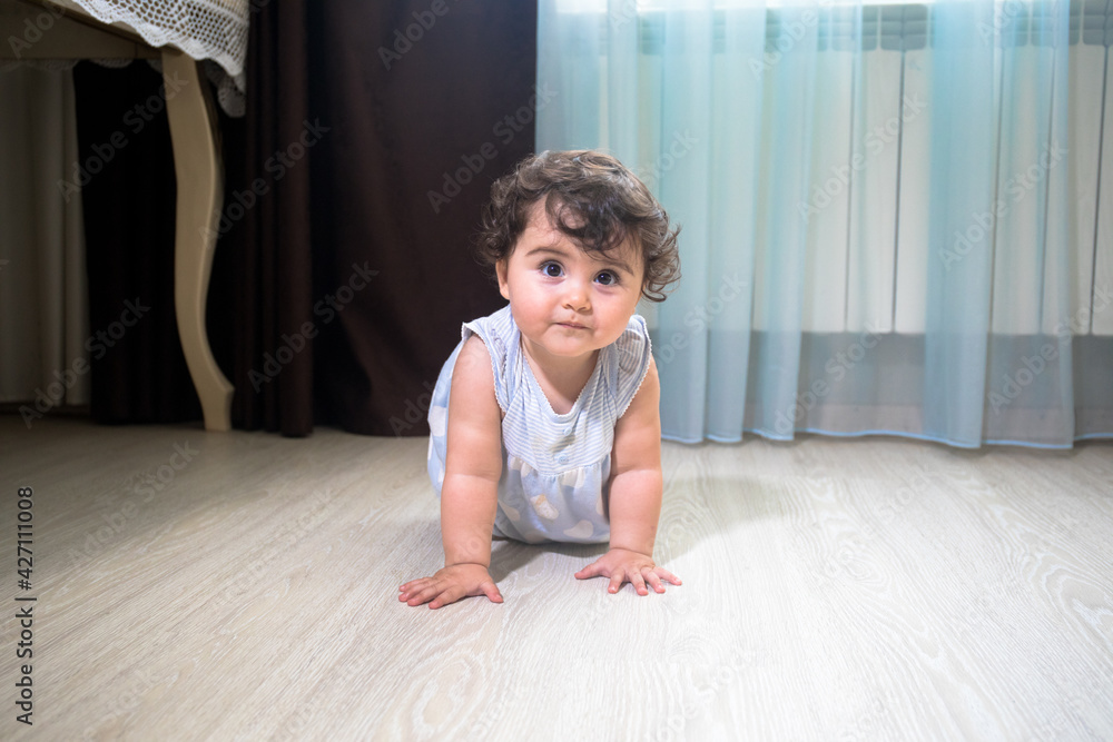 Baby Girl In Summer Dress Sit on wooden floor inside room.