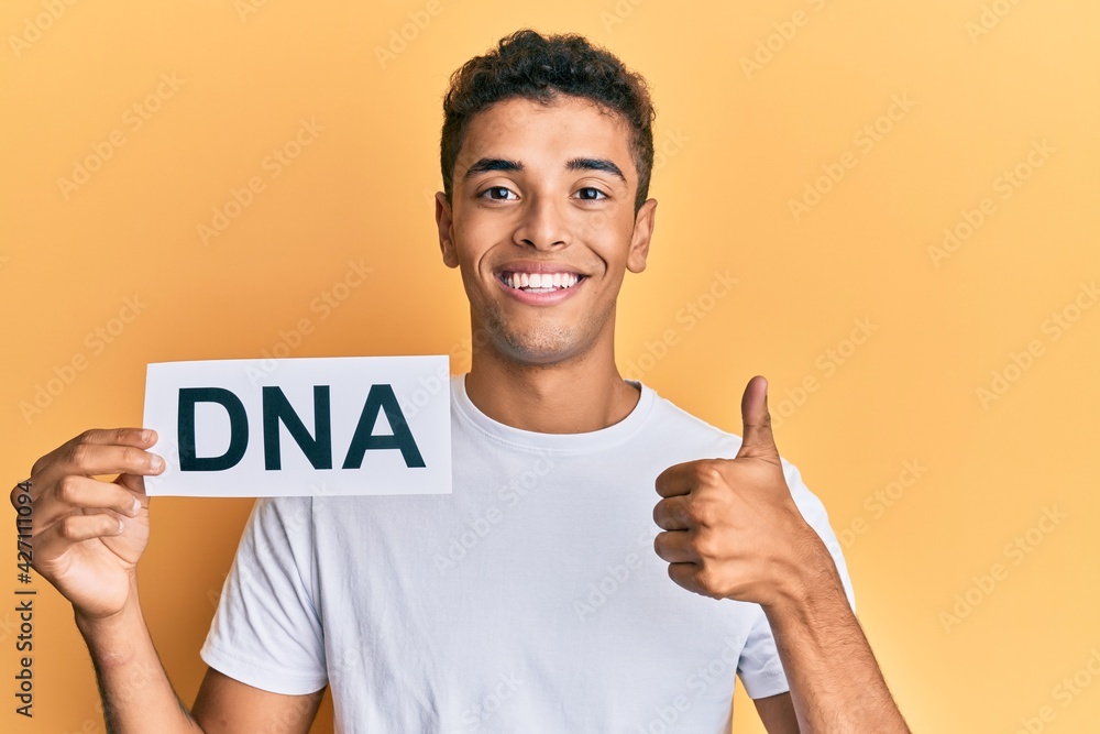 Young handsome african american man holding dna word smiling happy and positive, thumb up doing excellent and approval sign Young handsome african american man holding dna word smiling happy and positive, thumb up doing excellent and approval sign