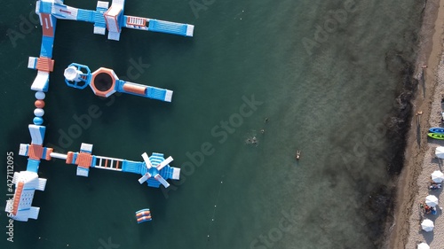 aerial view watersports, sea park, water fun activities, floating slides on the surface of the sea of paradise beach during summer holidays in greece