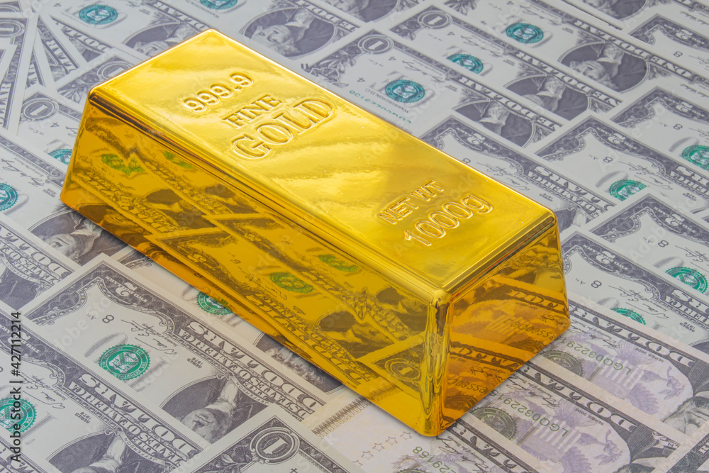 Calgary, Alberta, Canada. April 10, 2021. A Gold Bar or Golden Brick Bullion on American USA currency. Calgary, Alberta, Canada. April 10, 2021. A Gold Bar or Golden Brick Bullion on American USA currency.
