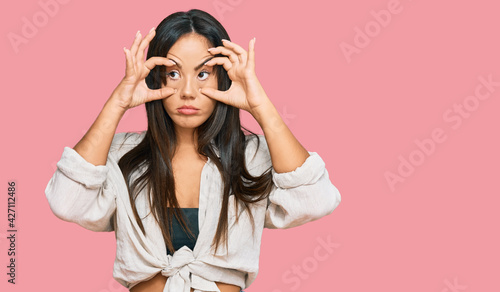 Young beautiful hispanic girl wearing casual clothes trying to open eyes with fingers, sleepy and tired for morning fatigue © Krakenimages.com