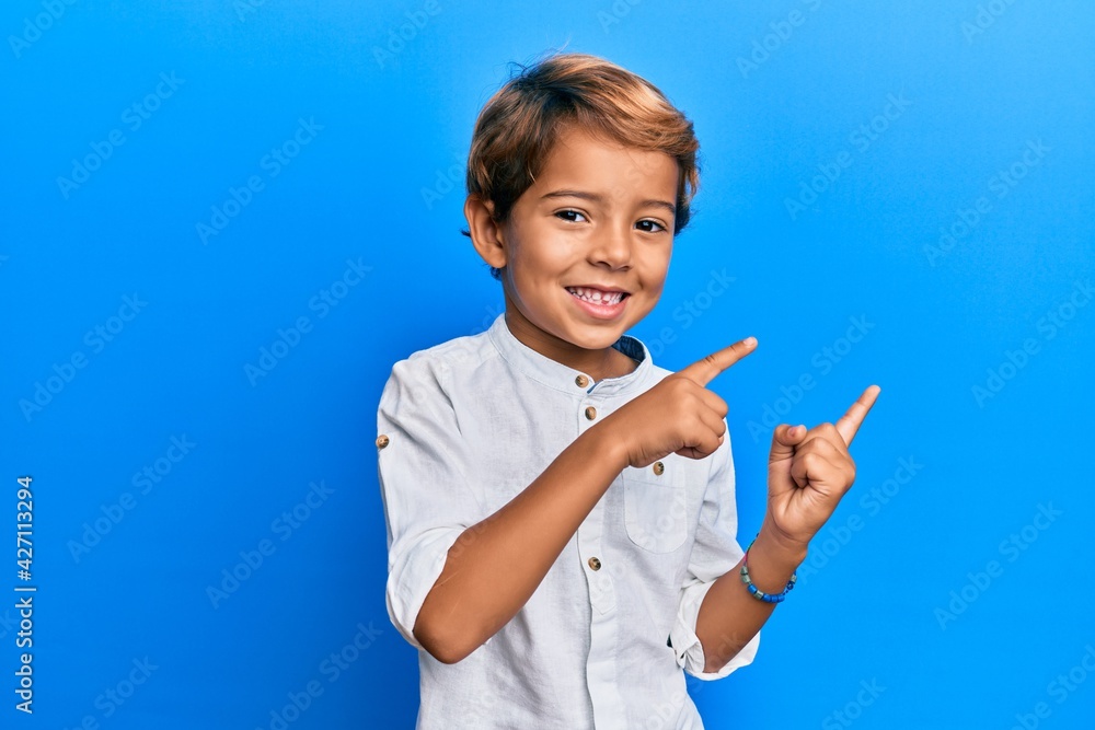 Adorable latin kid wearing casual clothes smiling and looking at the camera pointing with two hands and fingers to the side. Adorable latin kid wearing casual clothes smiling and looking at the camera pointing with two hands and fingers to the side.
