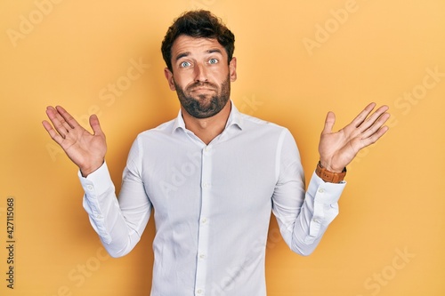 Handsome man with beard wearing casual white t shirt clueless and confused with open arms, no idea and doubtful face. © Krakenimages.com