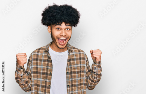 Young african american man with afro hair wearing casual clothes celebrating surprised and amazed for success with arms raised and open eyes. winner concept.