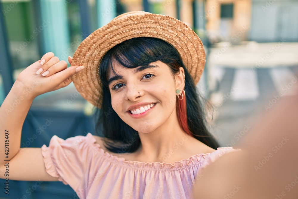 Young hispanic tourist girl wearing summer style making selfie by the camera at the city.